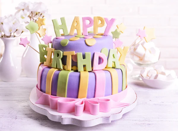 Delicious birthday cake on table on brick wall background — Stock Photo, Image