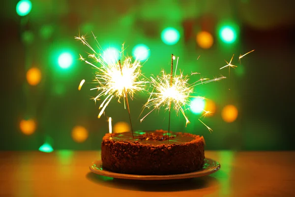 Tasty cake with sparklers on shiny background — Stock Photo, Image