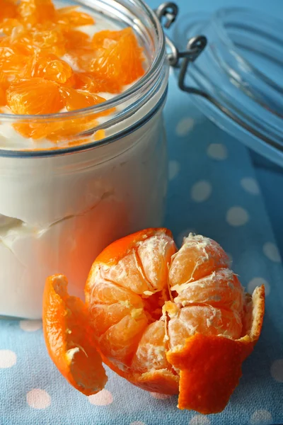 Dessert au lait savoureux avec des morceaux de mandarine fraîche dans un bocal en verre, sur fond de bois de couleur — Photo