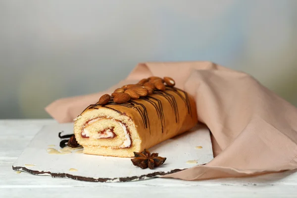 Délicieux gâteau roulé sur table en bois, sur fond clair — Photo