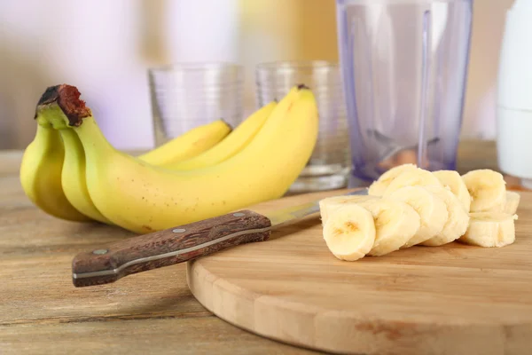 Sliced banana on cutting board, on wooden table, on bright background — Stock Photo, Image