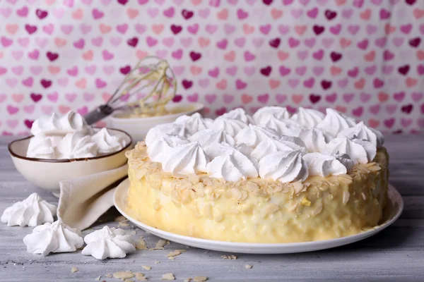 Tasty homemade meringue cake on wooden table, on pink background