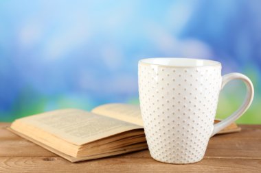 Fincan çay ve masaya parlak arka plan üzerinde kitap