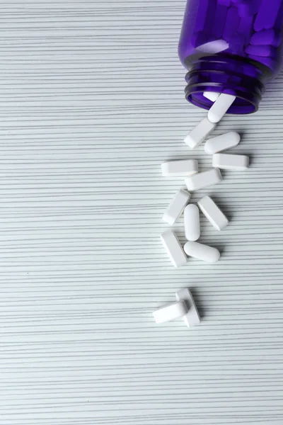 Pillole in bottiglia sul tavolo bianco — Foto Stock