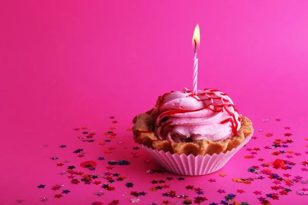 Birthday cup cake with candle and colorful stars on pink background — Stock Photo, Image