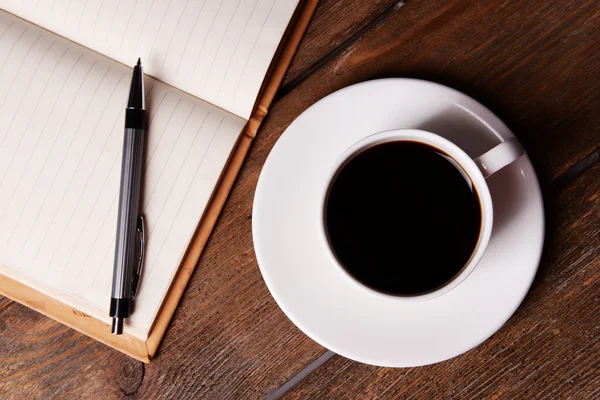 Cup of coffee on saucer with notebook — Stock Photo, Image
