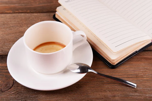 日記、ペンと木製のテーブル背景にスプーンでソーサーにコーヒーを 1 杯 — ストック写真