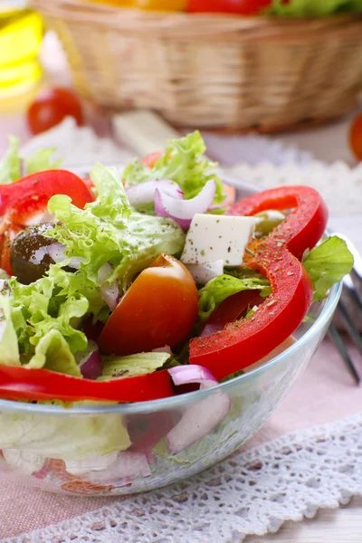 Ensalada griega en plato de vidrio con tenedor y fondo de verduras —  Fotos de Stock