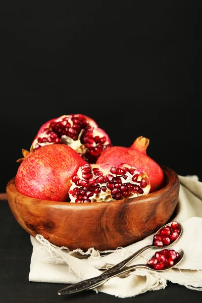 Juicy ripe pomegranates on wooden table, on dark background — Stock Photo, Image