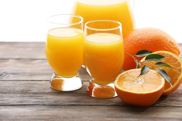 Copo de suco de laranja e fatias em fundo de mesa de madeira — Fotografia de Stock