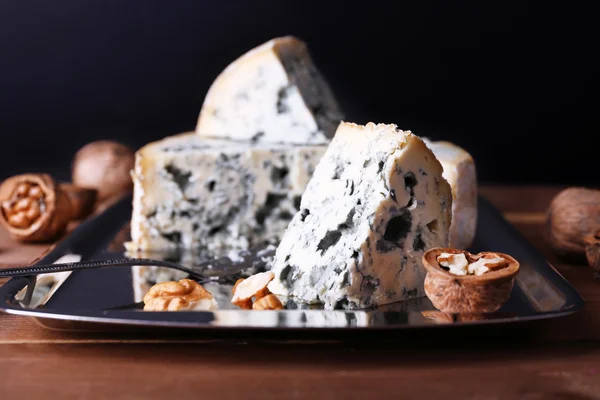 Blue cheese with nuts and blade on metal tray and wooden table and dark background — Stock Photo, Image