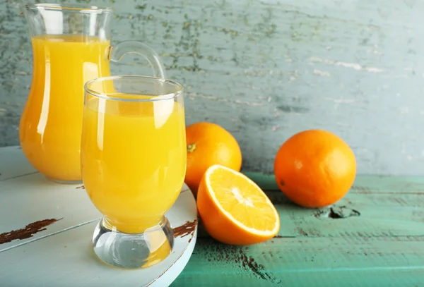 Glass of orange juice with slices on color wooden background — Stock Photo, Image