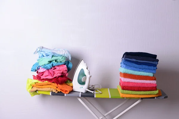 Asse da stiro con lavanderia su sfondo chiaro — Foto Stock