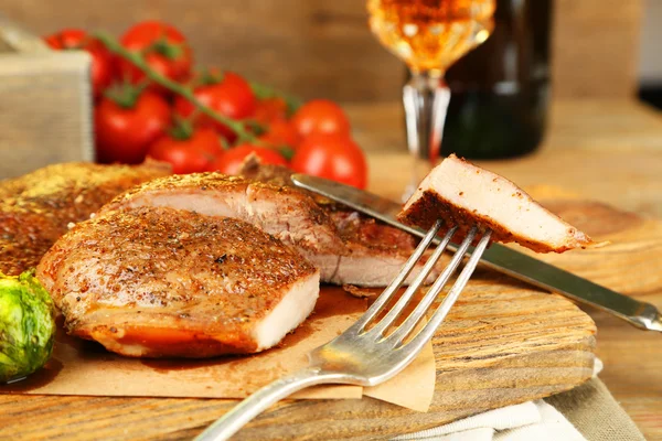 Roasted meat and vegetables on cutting board, on wooden table background — Stock Photo, Image