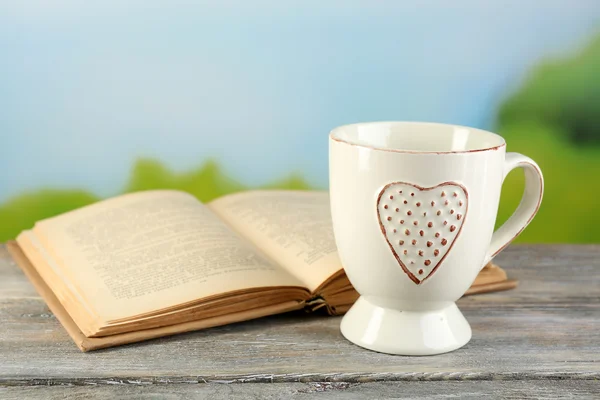Cup and book on table, on bright background — Stock Photo, Image