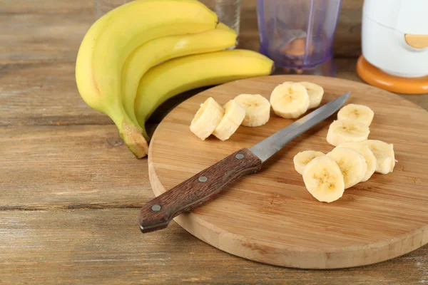 Plátky banánů na prkénko, na dřevěné pozadí — Stock fotografie