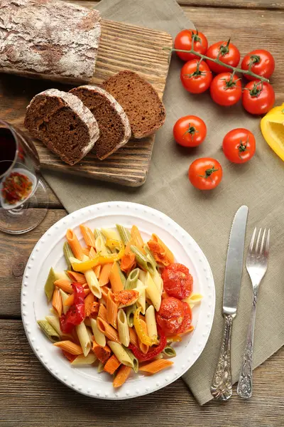 Pasta salad with pepper, carrot and tomatoes on wooden table background — Stock Photo, Image