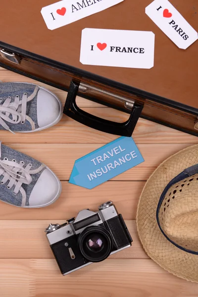 Suitcase and tourist stuff with inscription travel insurance on wooden background top view — Stock Photo, Image