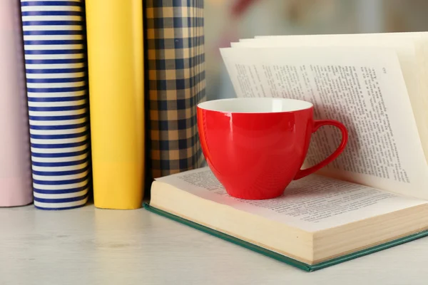 Color cup of tea with books on table, on light blurred background — Stock Photo, Image