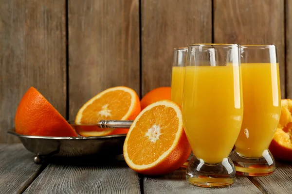 Copo de suco de laranja com fatias na bandeja de metal no fundo de madeira rústica — Fotografia de Stock