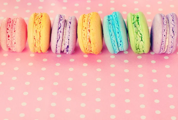 Tasty macaroons on pink polka dot background — Stock Photo, Image