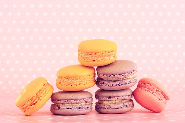 Tasty macaroons on pink polka dot background — Stock Photo, Image
