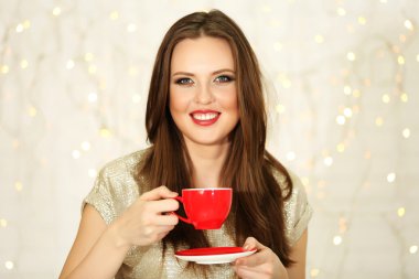 Işıklar arka plan üzerinde sıcak içecek fincan gülümseyen kız