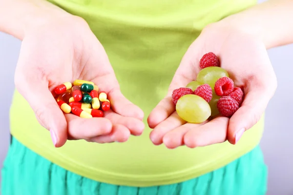 Frau mit Beeren und Pillen auf grauem Hintergrund — Stockfoto