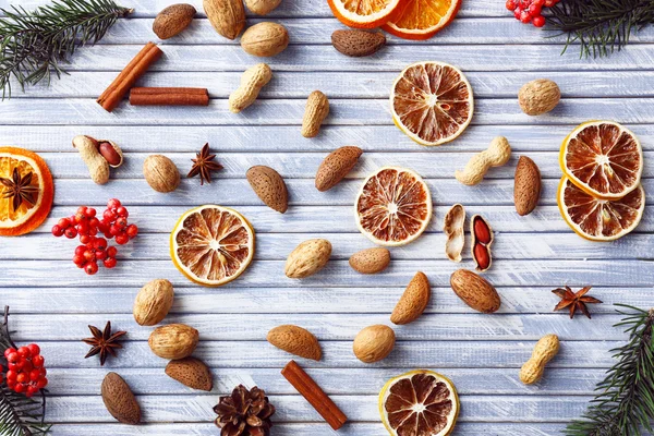 Rodajas de naranja seca y limón con frutos secos y especias sobre fondo de madera de color — Foto de Stock