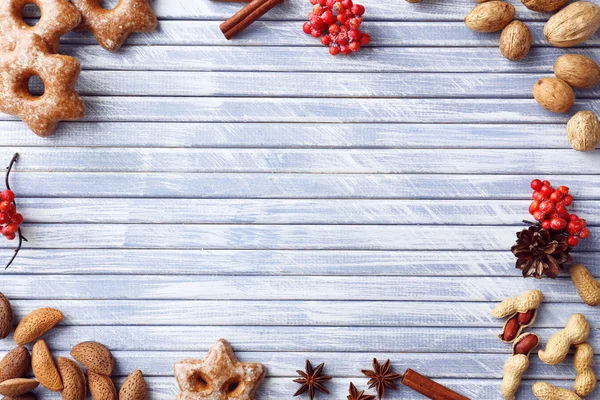 Marco navideño de galletas, nueces y especias sobre fondo de madera de color — Foto de Stock