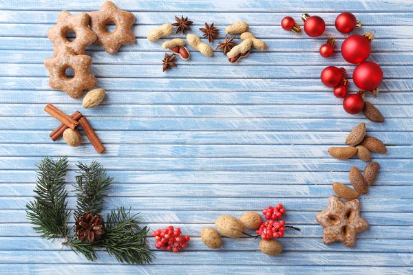 Christmas frame of cookies, nuts and spices on color wooden background — Stock Photo, Image