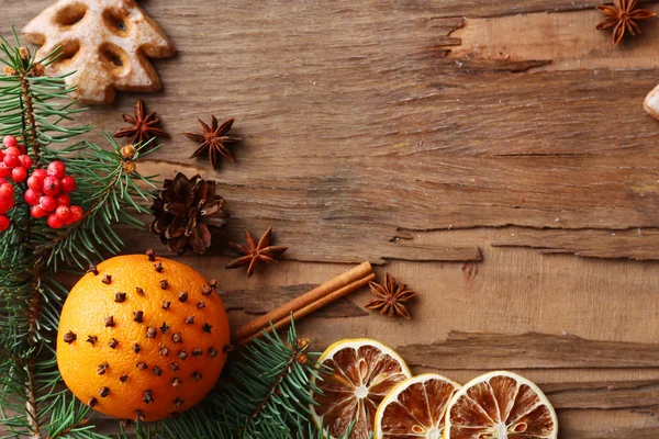 Oranje met koekjes, specerijen, segmenten van uitgedroogde citroen en takjes kerstboom op rustieke houten achtergrond — Stockfoto