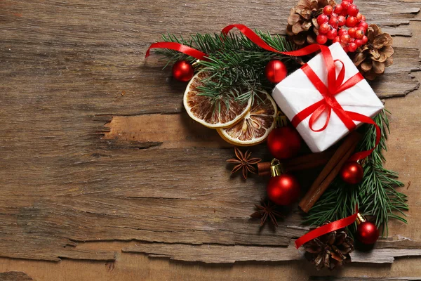 Rodajas de limón seco con caja de regalo, adornos y ramita de árbol de Navidad sobre fondo rústico de madera — Foto de Stock