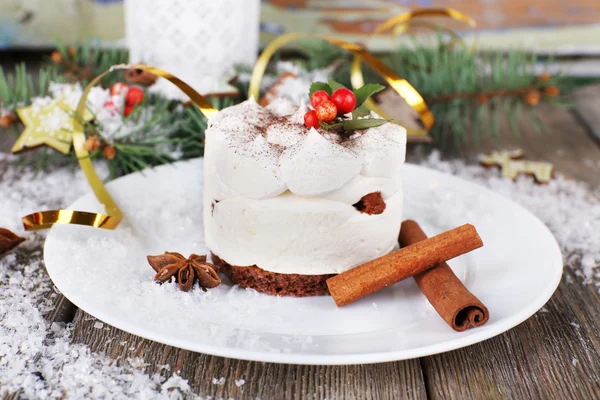 Delicious cake on plate with cinnamon and star anise on Christmas decoration background