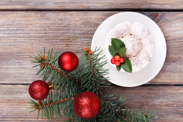 Délicieux gâteau sur soucoupe avec houx et baies sur décoration de Noël et fond en bois — Photo