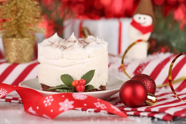 Delicious cake on saucer with holly and berry on bright Christmas decoration background — Stock Photo, Image