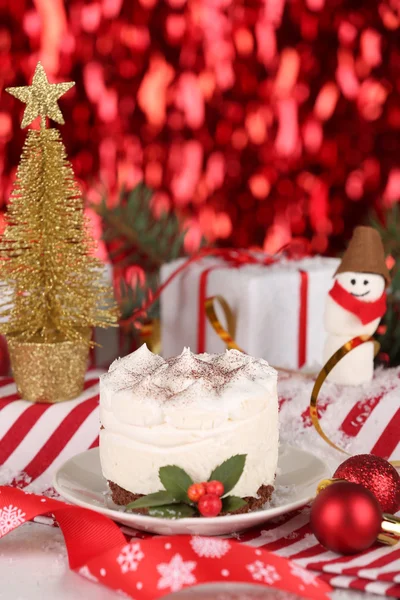 Leckeren Kuchen auf Untertasse mit Stechpalme und Beere auf hellen Weihnachtsdekoration Hintergrund — Stockfoto