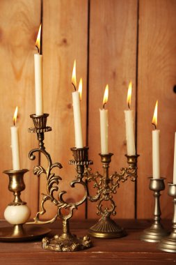 Retro candlesticks with candles on wooden background clipart