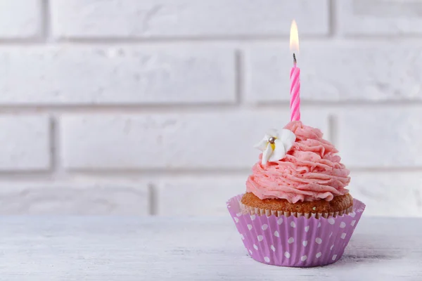 Delicioso aniversário cupcake na mesa no fundo da parede de tijolo — Fotografia de Stock