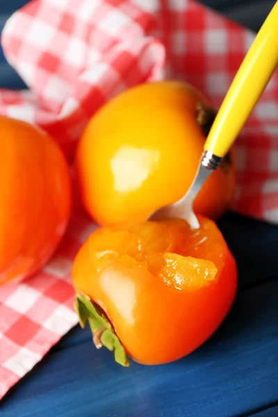 Mogen sharonfrukt på färg trä bakgrund — Stockfoto