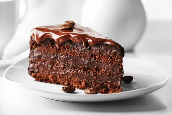 Köstlicher Schokoladenkuchen auf Teller auf Tisch vor hellem Hintergrund — Stockfoto