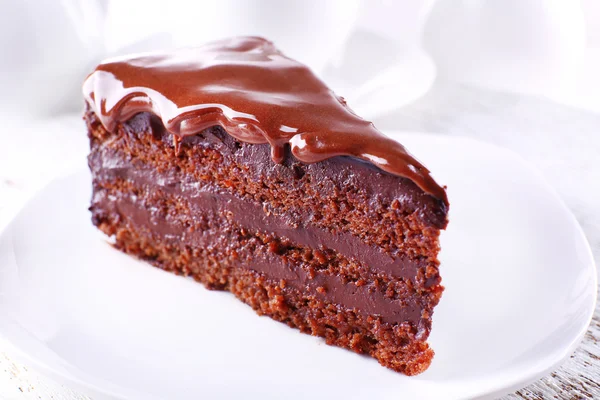 Delicioso bolo de chocolate na placa na mesa no fundo claro — Fotografia de Stock