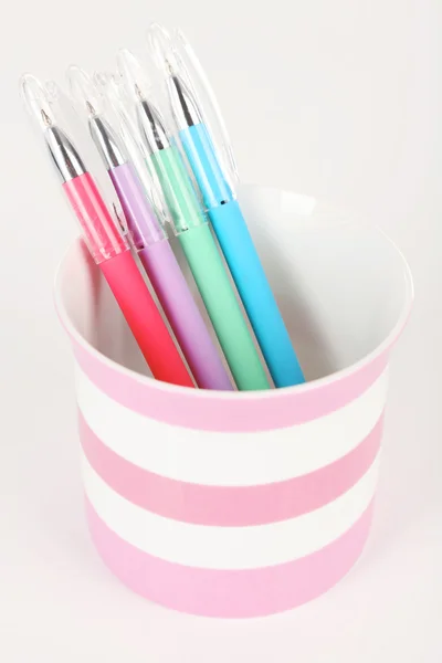 Красочные ручки в полосатой пластиковой чашке изолированы на белом фоне — стоковое фото