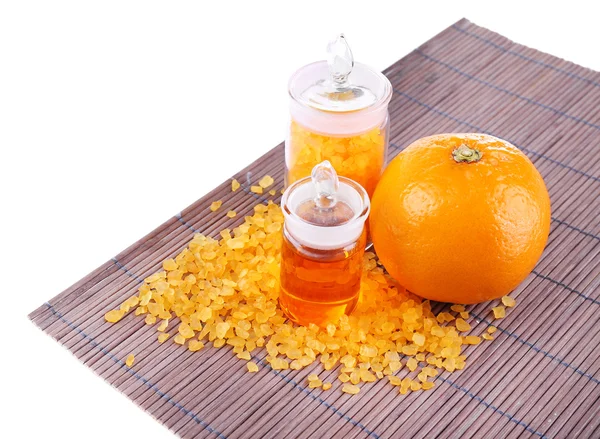 Botellas de aceite esencial y sal de baño cerca de la naranja en la estera de bambú aislado en blanco —  Fotos de Stock