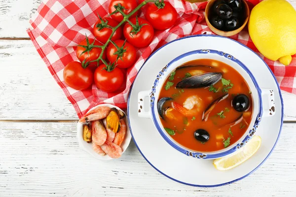 Sopa sabrosa con gambas, mejillones, tomates y aceitunas negras en un bol sobre fondo de madera —  Fotos de Stock