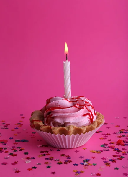 Bolo de xícara de aniversário com vela e estrelas coloridas no fundo rosa — Fotografia de Stock