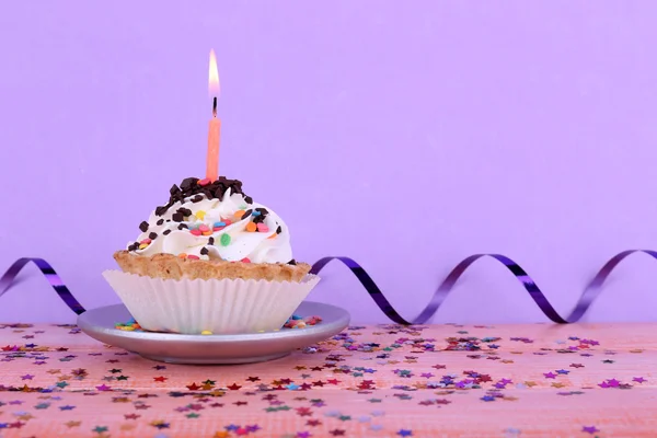 Geburtstagstorte mit Kerze mit Sekt auf Teller auf farbigem Holztisch und hellem Hintergrund — Stockfoto