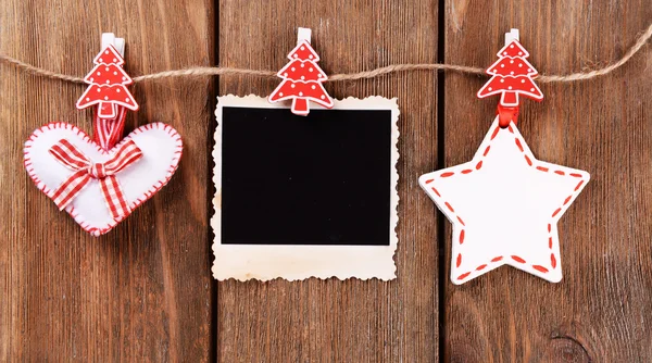 Marco de fotos en blanco y decoración de Navidad en cuerda, sobre fondo de madera —  Fotos de Stock