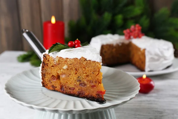 Fatia de bolo coberto de creme com decoração de Natal na mesa, no fundo da parede de madeira — Fotografia de Stock