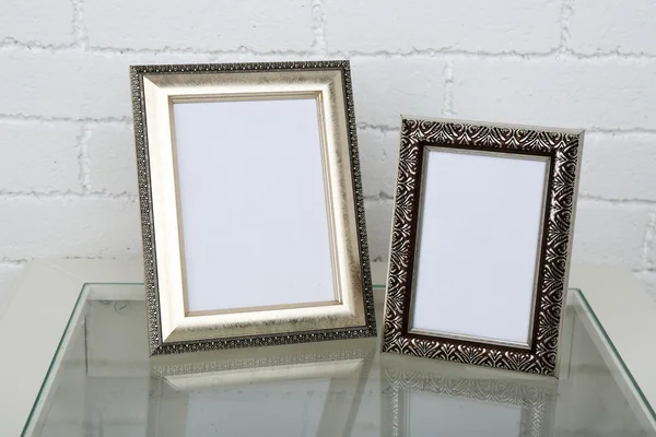 Photo frames on coffee table on brick wall background — Stock Photo, Image